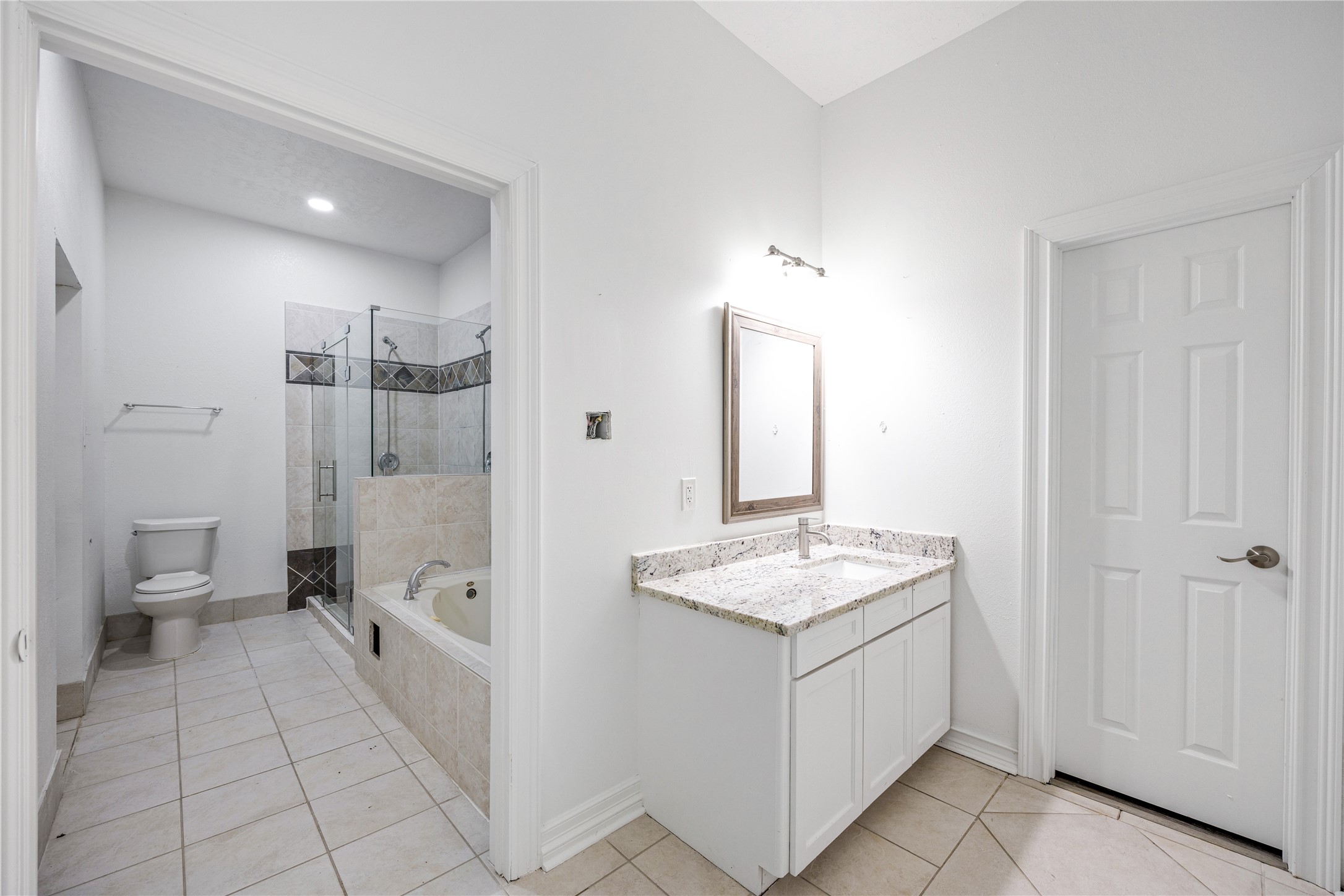 15015 House Road Cypress, TX 77433 - Photo 48 of 50 Modern bathroom with white walls and tile flooring. Features a glass-enclosed shower, separate bathtub, and granite countertop vanity. Bright and spacious with a clean look.