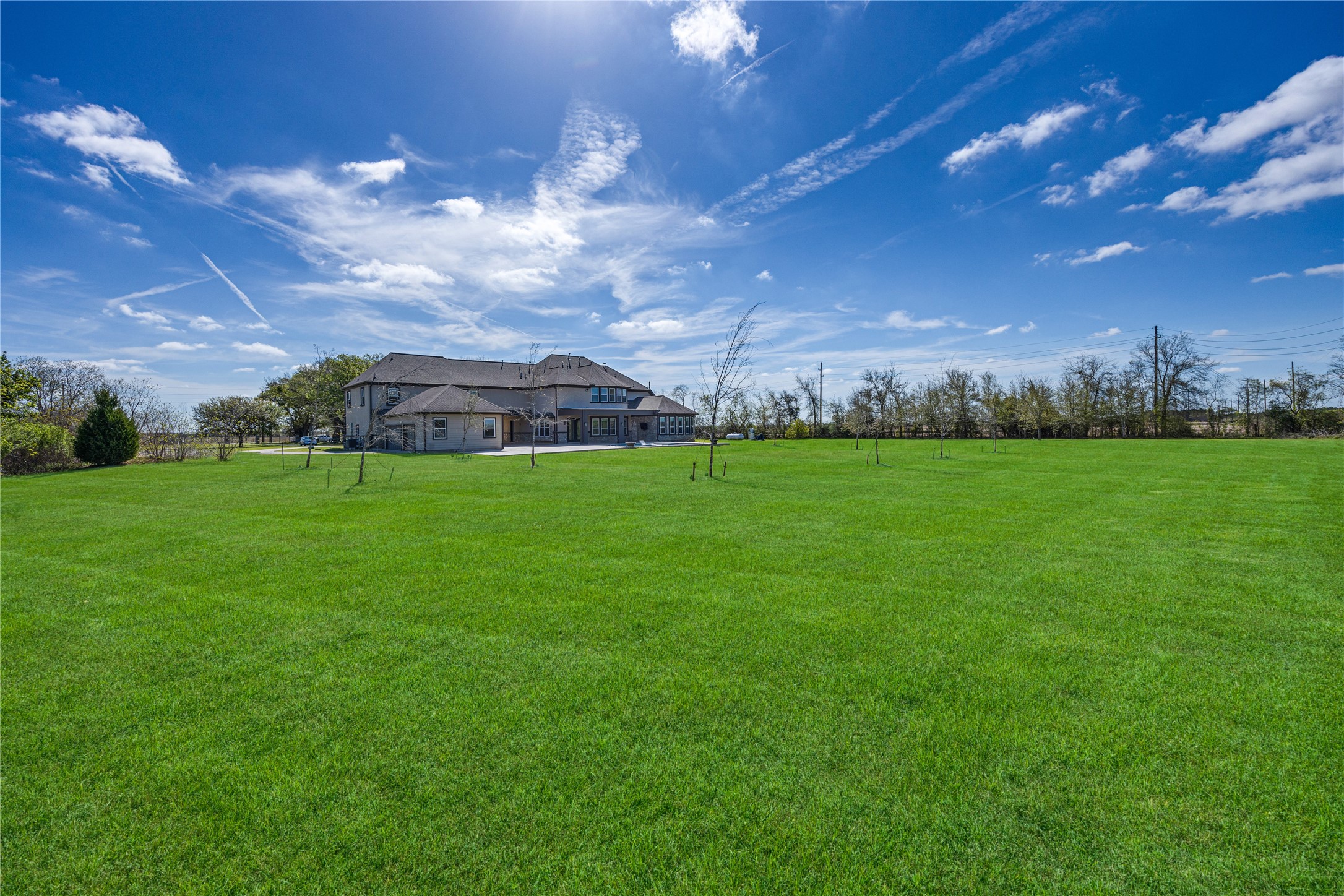 15015 House Road Cypress, TX 77433 - Photo 6 of 50 This photo showcases a spacious property with a large, lush green lawn and a sizable, modern house in the background. The setting is open and peaceful, ideal for privacy and outdoor activities.