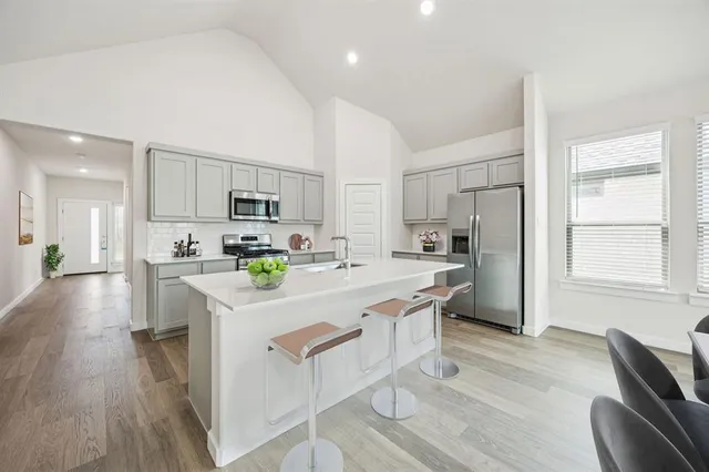 a kitchen with stainless steel appliances a refrigerator stove a sink and a oven with wooden floor