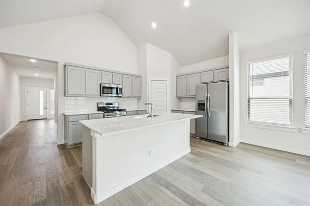 a kitchen with stainless steel appliances granite countertop a sink stove microwave and refrigerator