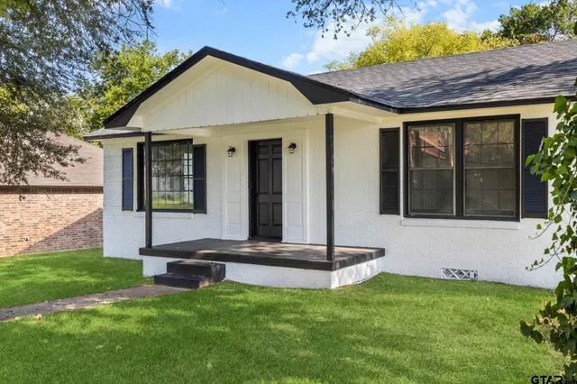 a view of a backyard with a garden and a large tree