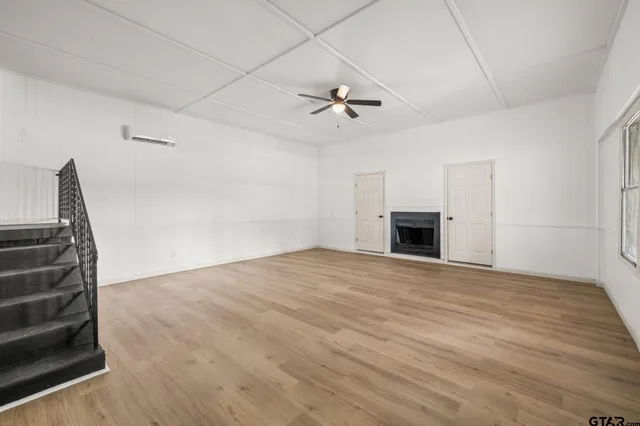 a view of empty room with a fireplace and wooden floor
