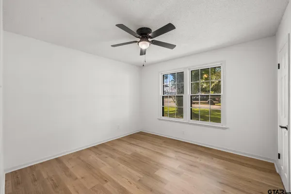 an empty room with wooden floor and windows