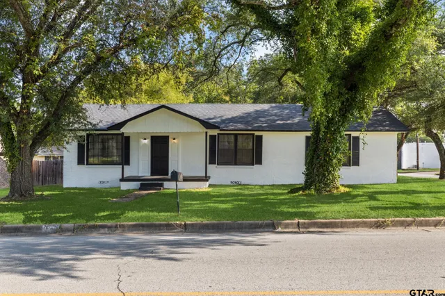 a front view of a house with a garden and trees