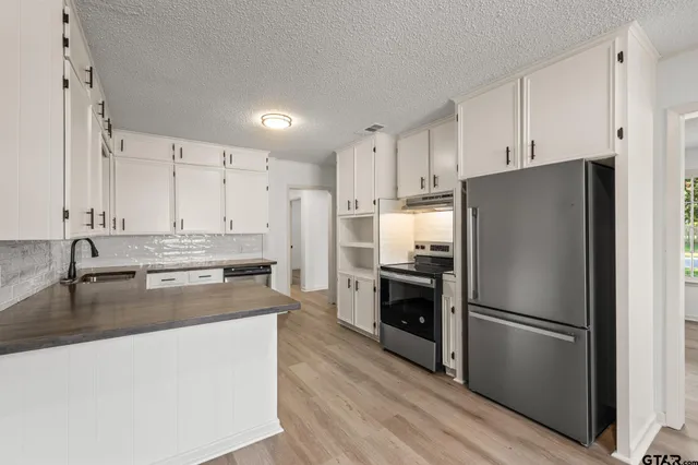 a kitchen with kitchen island granite countertop appliances cabinets and wooden floor