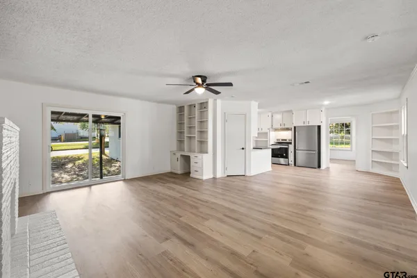 a view of an empty room with a window and wooden floor