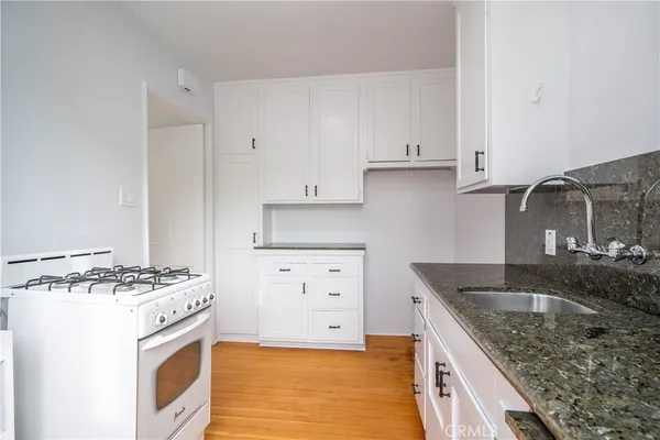 a kitchen with granite countertop a sink stove and cabinets