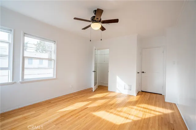 a view of a bedroom with wooden floor and a ceiling fan