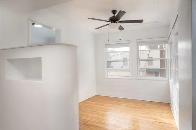 a view of empty room with wooden floor and fan