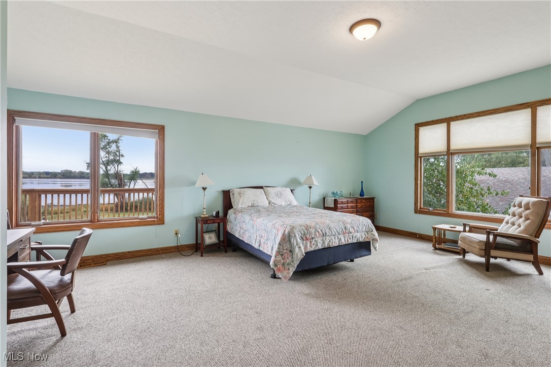 337 Cedar Point Road Sandusky, OH 44870 - Photo 21 of 50 Bedroom with multiple windows, vaulted ceiling, carpet floors, and a water view