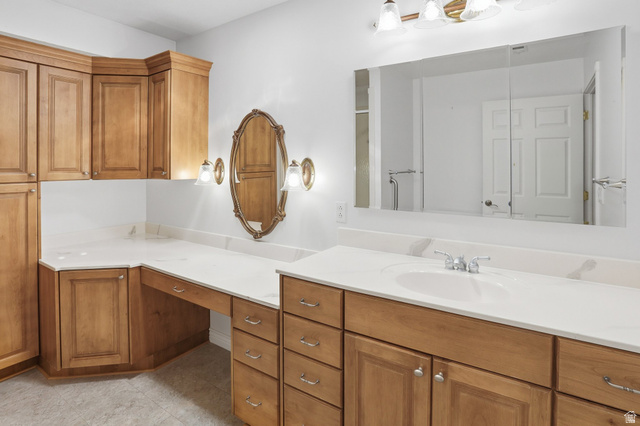 2190 750 West Perry, UT 84302 - Photo 28 of 42 Spacious bathroom vanity featuring light wood cabinetry, white countertops, an integrated sink with a chrome faucet, a large mirrored medicine cabinet, and an additional ornate oval mirror with sconce lighting
