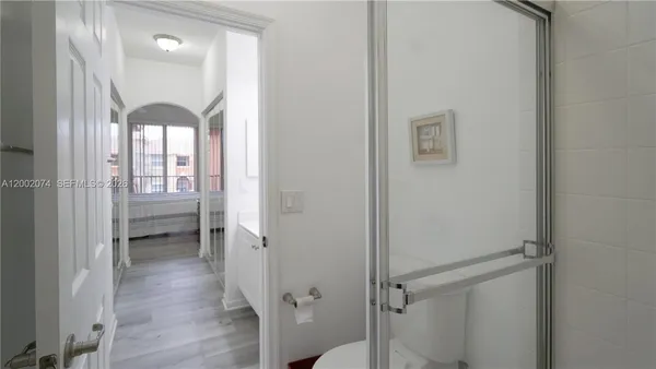 a hallway with wooden floor chandelier and a bathroom