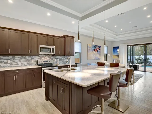 a kitchen with kitchen island granite countertop a table chairs microwave and cabinets