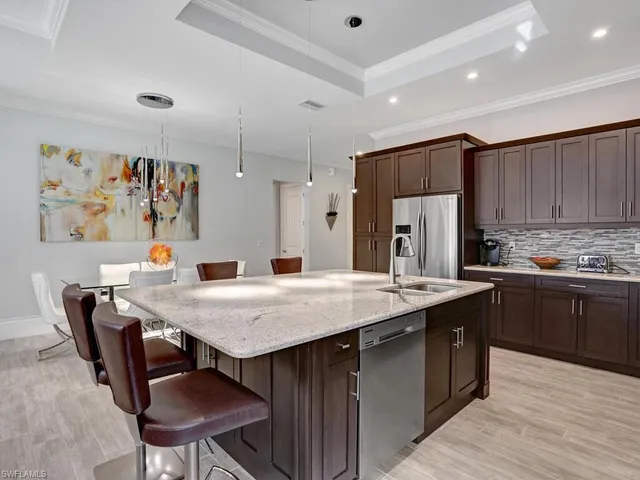 a kitchen with stainless steel appliances granite countertop a table chairs sink refrigerator and cabinets