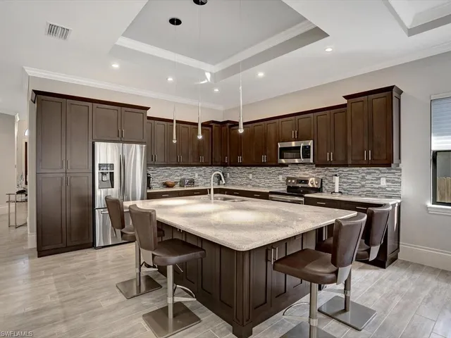 a kitchen with stainless steel appliances granite countertop a table chairs sink refrigerator and microwave