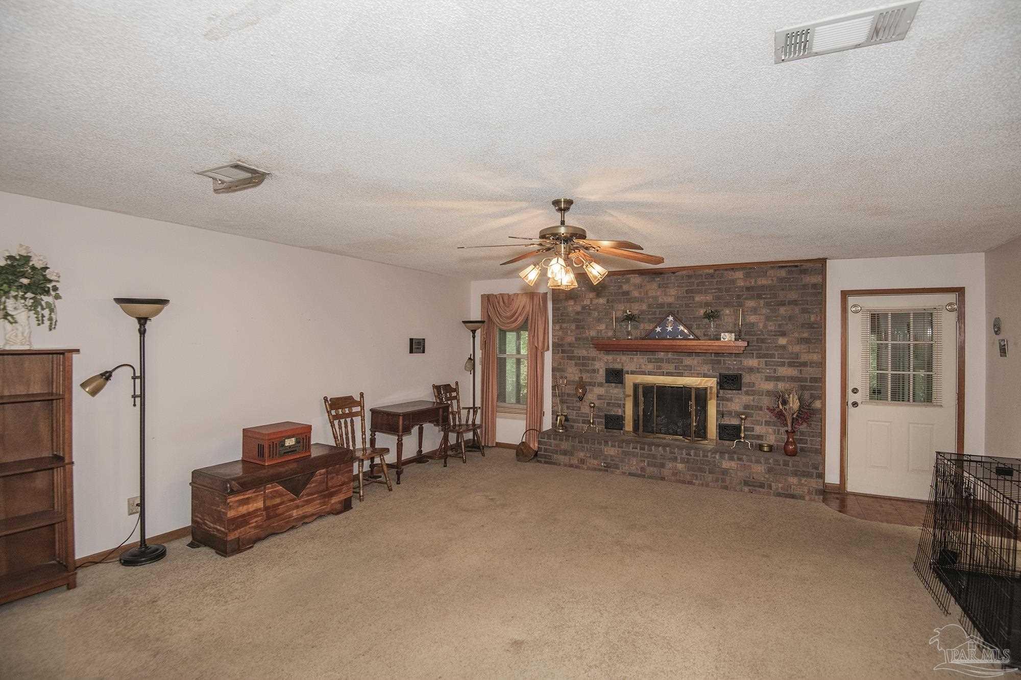 1210 Goldenrod Road Cantonment, FL 32533 - Photo 14 of 50 a living room with furniture a fireplace and a chandelier