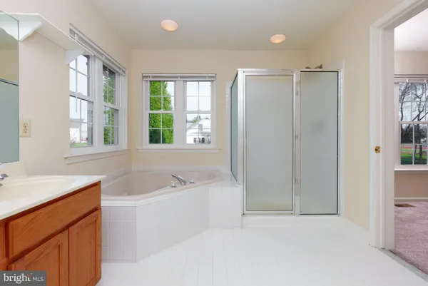 a bathroom with a bathtub a shower a sink and a window