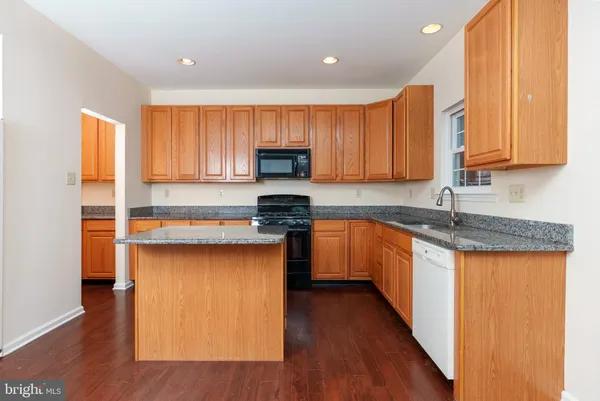 a kitchen with granite countertop wooden floors a sink and a stove