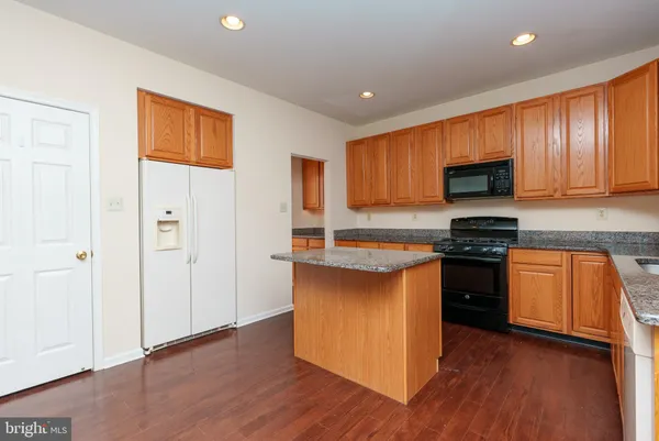 a kitchen with granite countertop wooden floors a stove and a refrigerator