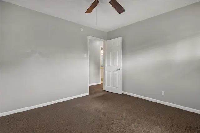 an empty room with view of a ceiling fan and window