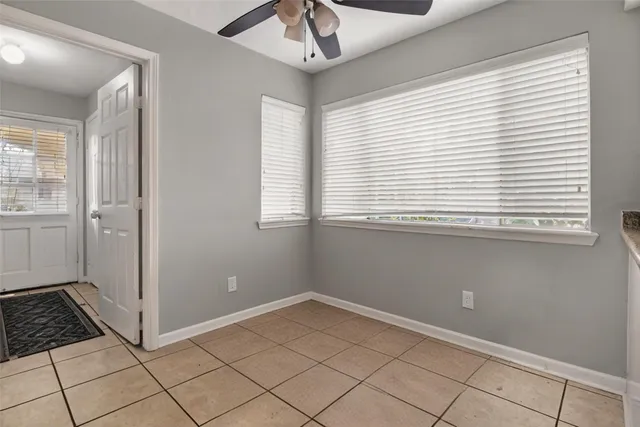 a view of an empty room with window and chandelier fan