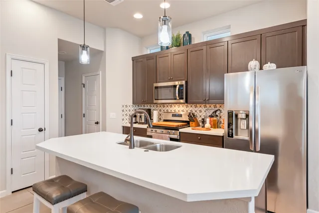 a kitchen with kitchen island a refrigerator stove and sink