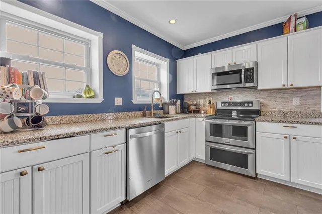 a kitchen with granite countertop white cabinets and stainless steel appliances
