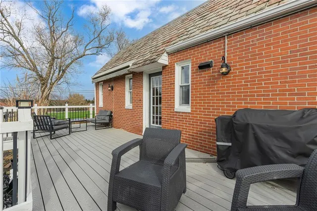 a backyard of a house with wooden floor chairs sofa and barbecue oven