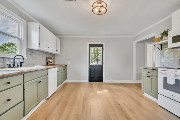 a kitchen with granite countertop a stove a sink and a white cabinets