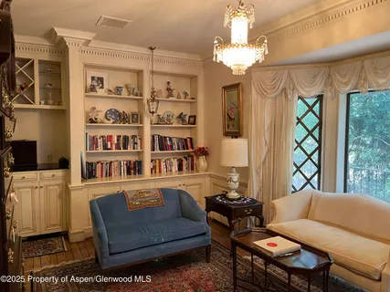 a living room with furniture a chandelier and a bookshelf