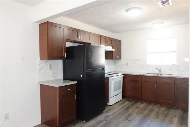 a kitchen with stainless steel appliances granite countertop a refrigerator and a sink