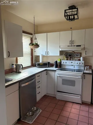 a kitchen with stainless steel appliances granite countertop a sink a stove a chimney and a cabinets