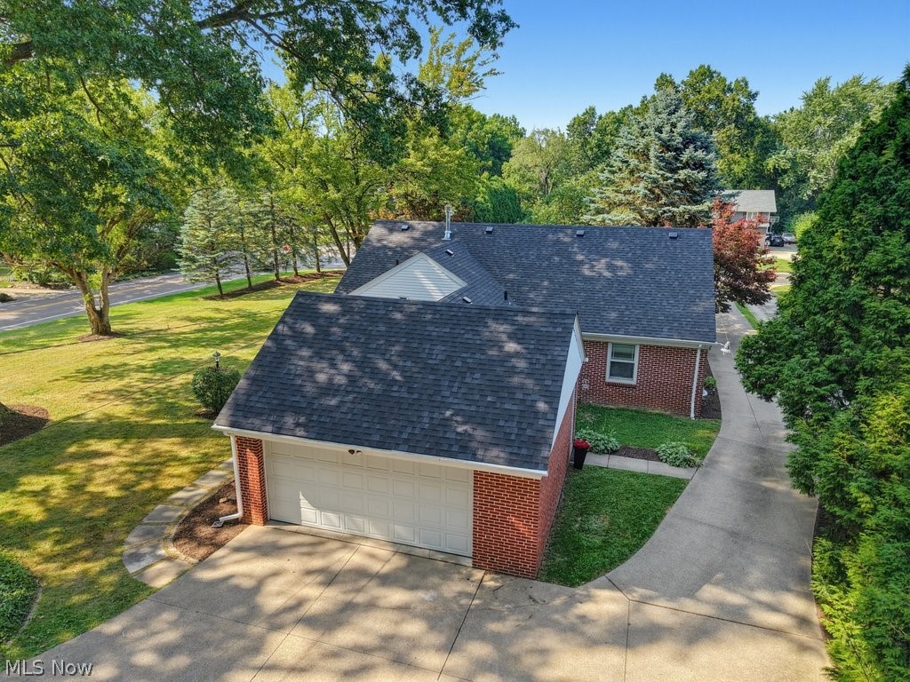 2468 Ridgewood Road Akron, OH 44313 - Photo 42 of 50 Brick exterior with dark shingle roofing, attached garage, concrete driveway, and established landscaping