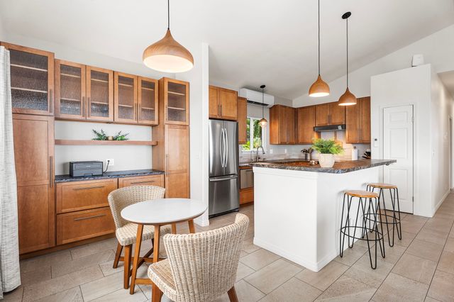 a kitchen with stainless steel appliances granite countertop a refrigerator a stove a sink dishwasher and a dining table with wooden floor