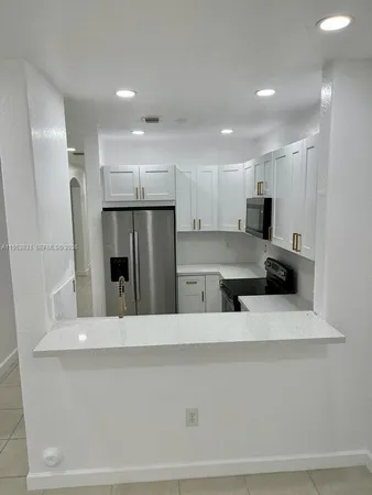 a large kitchen with a large counter top stainless steel appliances and cabinets