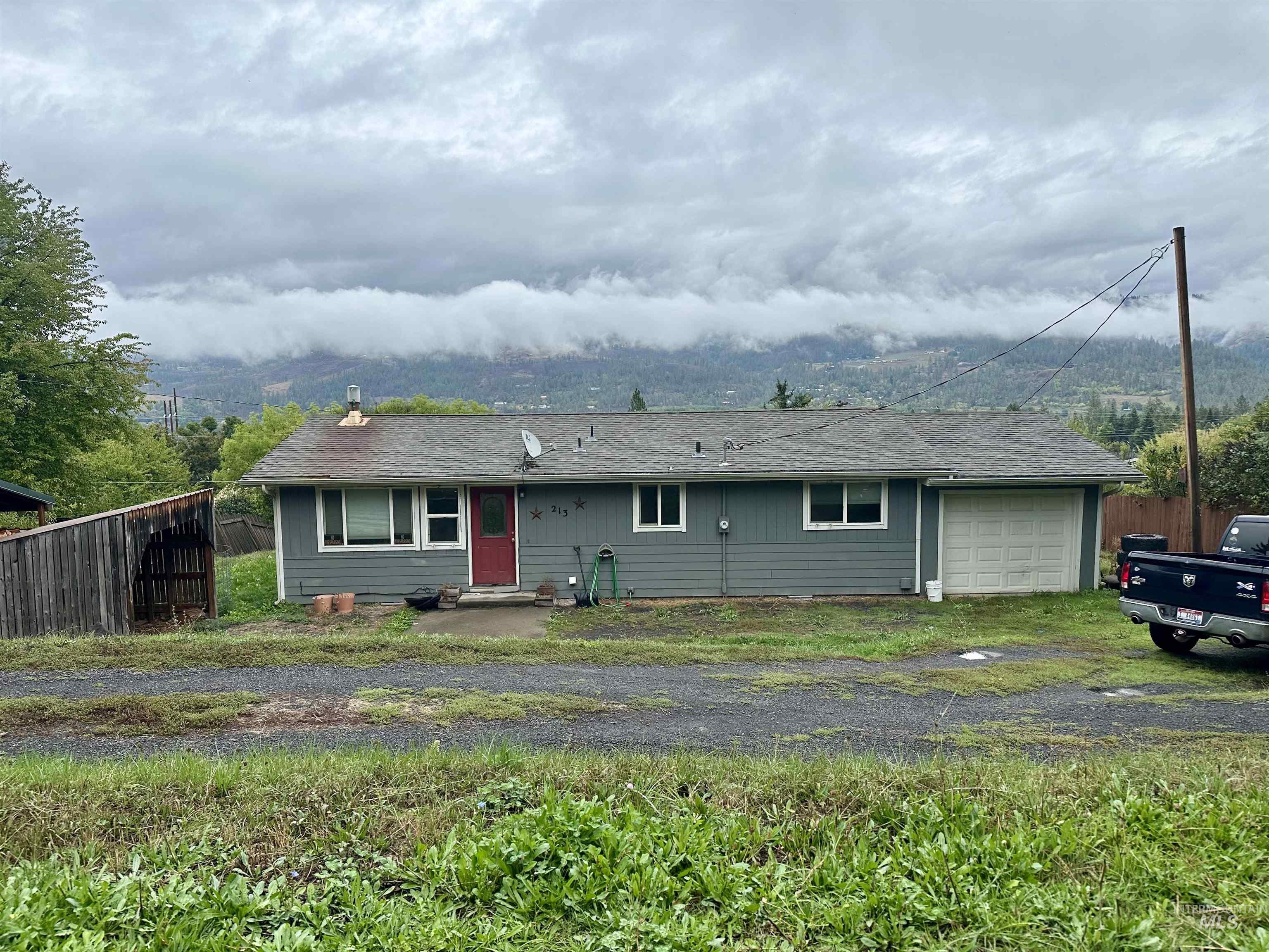 Ranch-style home featuring roof with shingles, an attached garage, and driveway