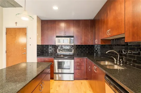 a large kitchen with kitchen island a large counter top stainless steel appliances a sink and cabinets