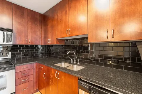 a kitchen with stainless steel appliances granite countertop a sink a stove and a refrigerator