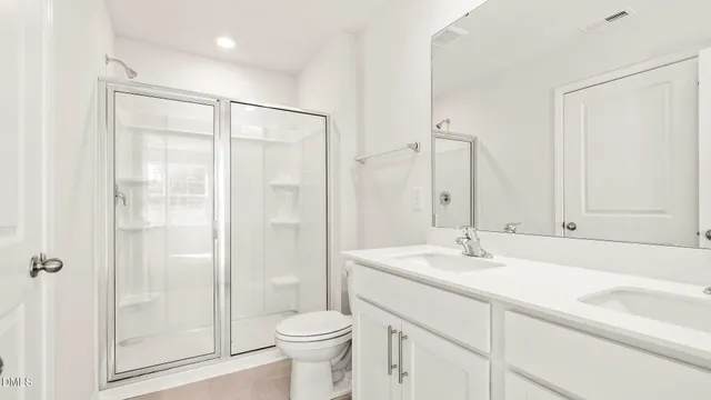 a bathroom with a double vanity sink toilet and shower