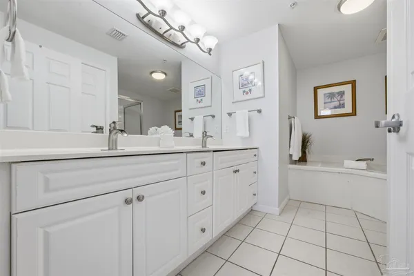 a spacious en suite bathroom with a double sink and mirror