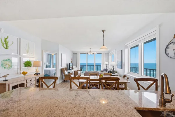 a living room with furniture a dining table and a potted plant with wooden floor