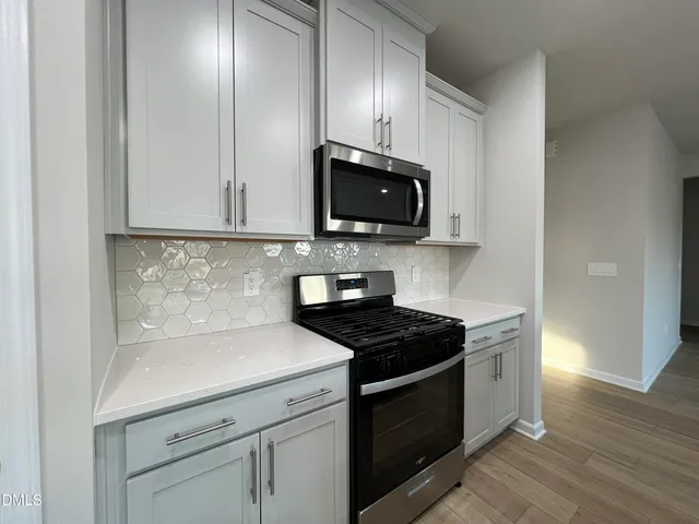 a kitchen with stainless steel appliances granite countertop a stove a microwave and a white cabinets