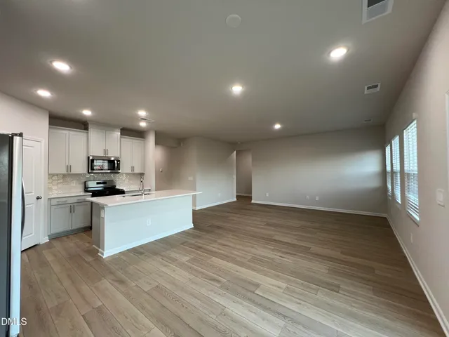 a view of kitchen with kitchen island granite countertop stainless steel appliances refrigerator sink and microwave