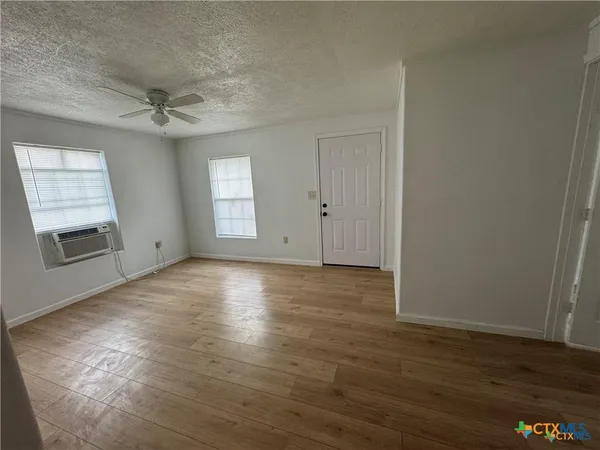an empty room with wooden floor and windows