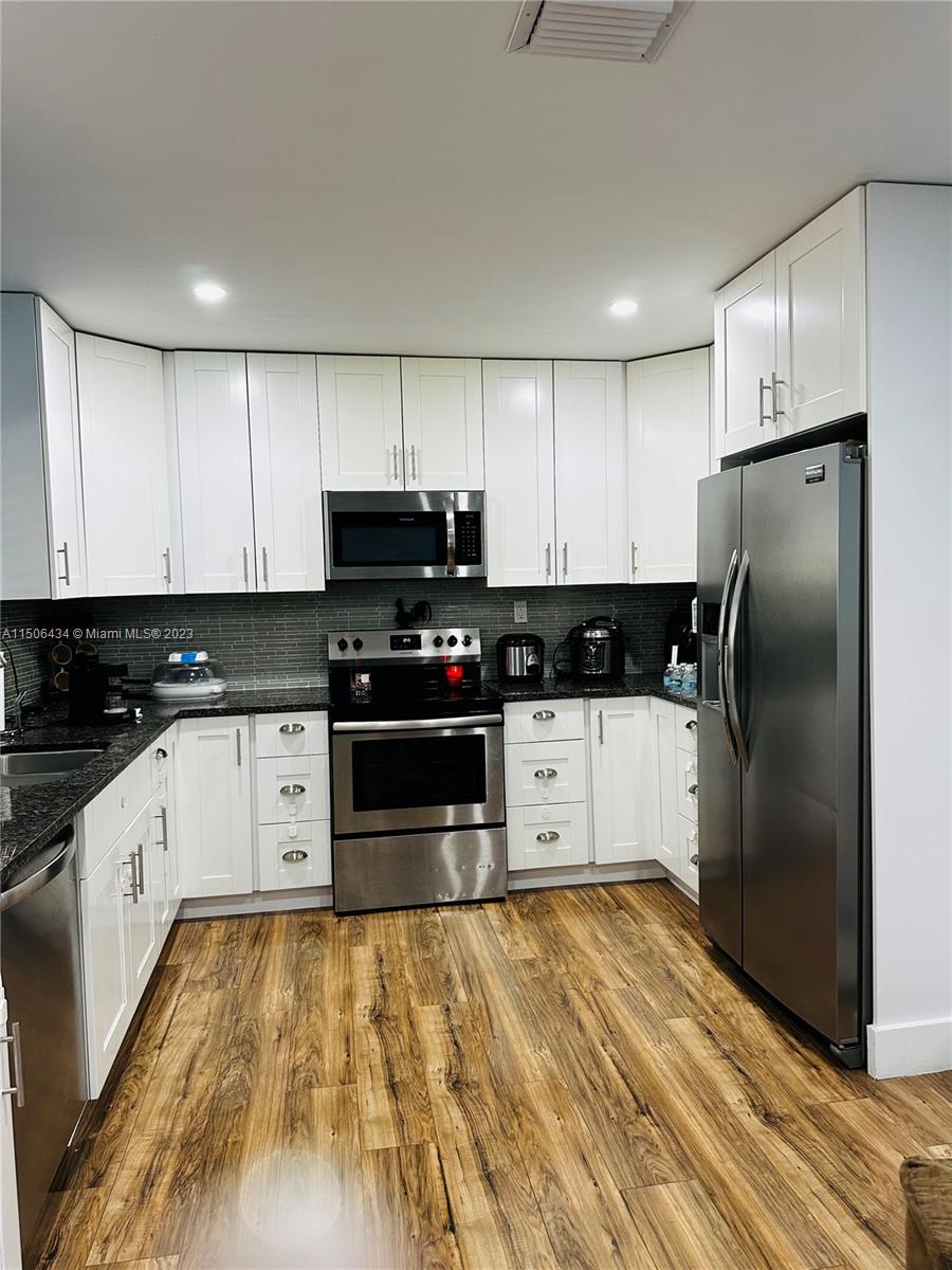 26232 Southwest 124th Place Homestead, FL 33032 - Photo 6 of 33 a kitchen with granite countertop a refrigerator and a stove top oven