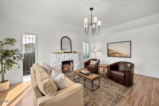 a living room with furniture a chandelier and wooden floor