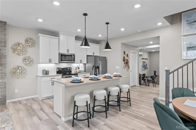 a kitchen with stainless steel appliances kitchen island granite countertop a stove a sink a dining table and chairs with wooden floor