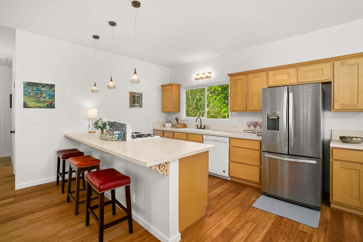 6390 Kalama Road Kapaa, HI 96746 - Photo 6 of 21 a kitchen with a refrigerator a stove a sink dishwasher with a dining table and wooden floor