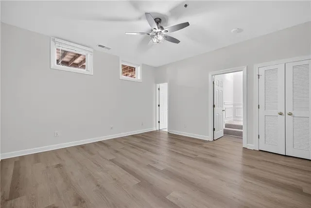 an empty room with wooden floor and ceiling fan