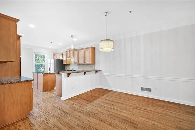 a open kitchen with stainless steel appliances granite countertop a refrigerator a sink dishwasher a stove and white countertops with wooden floor